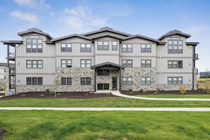 A multi-story residential building with a stone facade and multiple windows. - Deer Valley East Retreat | Shuttle to Skiing | Pool & Hot Tub (Heber City)