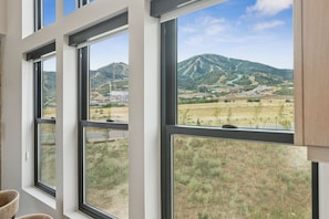 Ein Zimmer mit großen Fenstern und Blick auf eine gebirgige Landschaft.