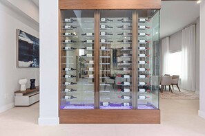 Ein modernes Interieur mit Weinkühler, Kaffeemaschine und Essbereich mit Stühlen und Tisch.