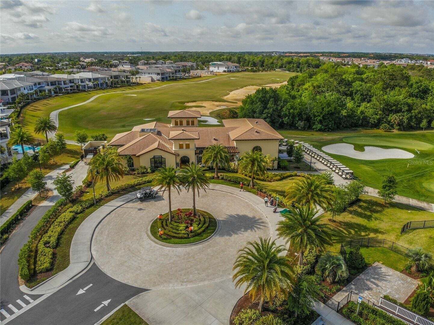 Un parcours de golf doté d’un club-house, de palmiers et d’une pelouse bien entretenue.