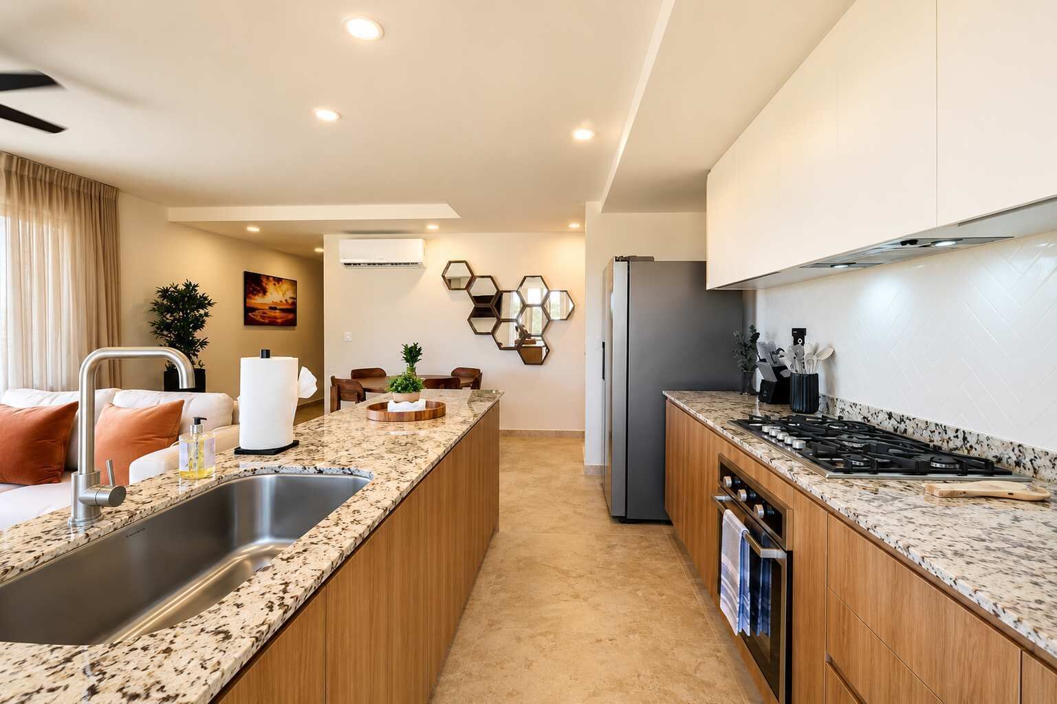 Una cocina moderna con encimeras de granito, electrodomésticos de acero inoxidable y una isla central.