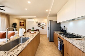 Une cuisine moderne dotée de plans de travail en granit, d’appareils électroménagers en acier inoxydable et d’un îlot central.
