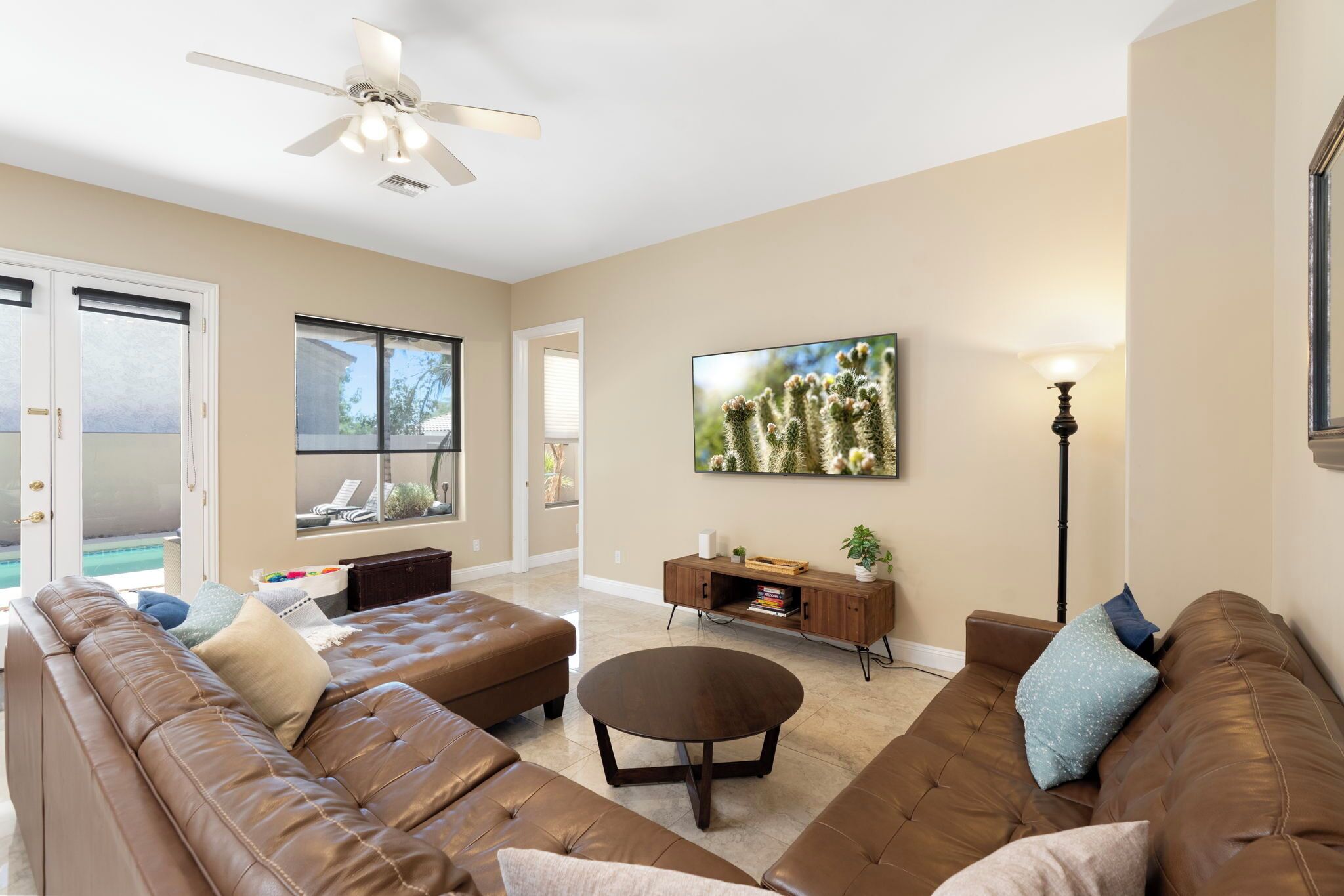A living room with a brown leather sofa, a round coffee table, and a ceiling fan.