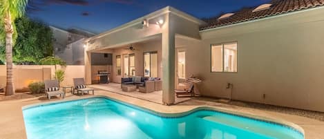 A residential property with a swimming pool, outdoor seating area, and a covered patio.