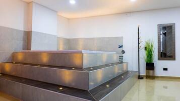 Zona de recepción con diseño moderno, que incluye un mostrador de recepción, una escalera y una planta en maceta.