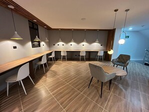 Un comedor moderno con una larga mesa de madera, sillas blancas e iluminación colgante.