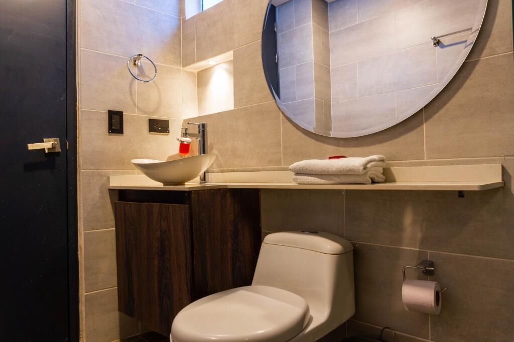 A modern bathroom with a toilet, a sink, a mirror, and a towel rack.