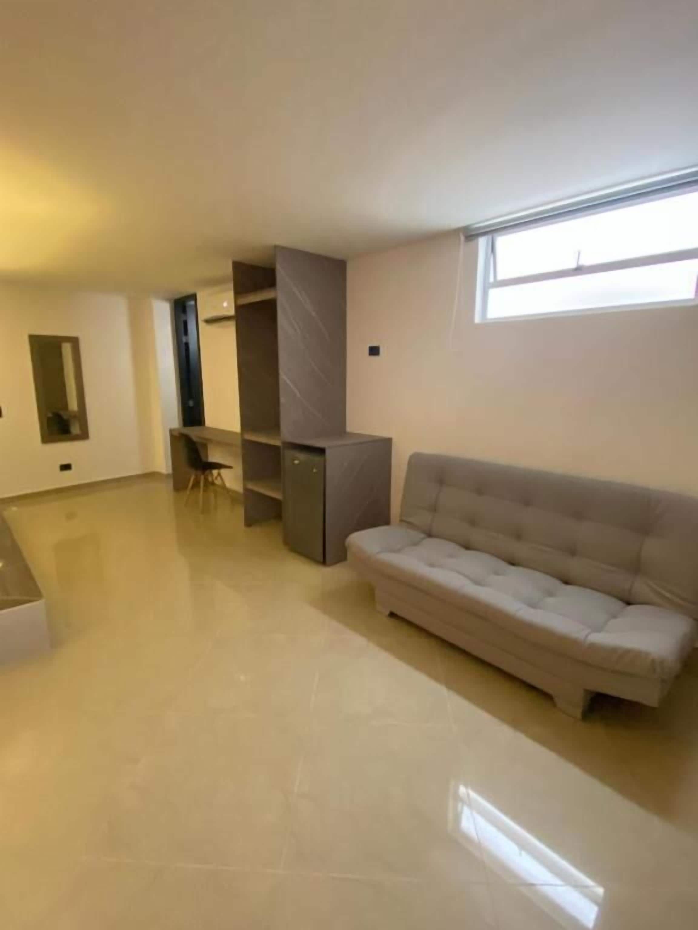 Una habitación amplia con un ventanal grande, un sofá y estanterías empotradas.