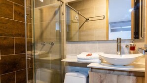 Un baño moderno con ducha envuelta en vidrio, un lavamanos blanco y un inodoro.