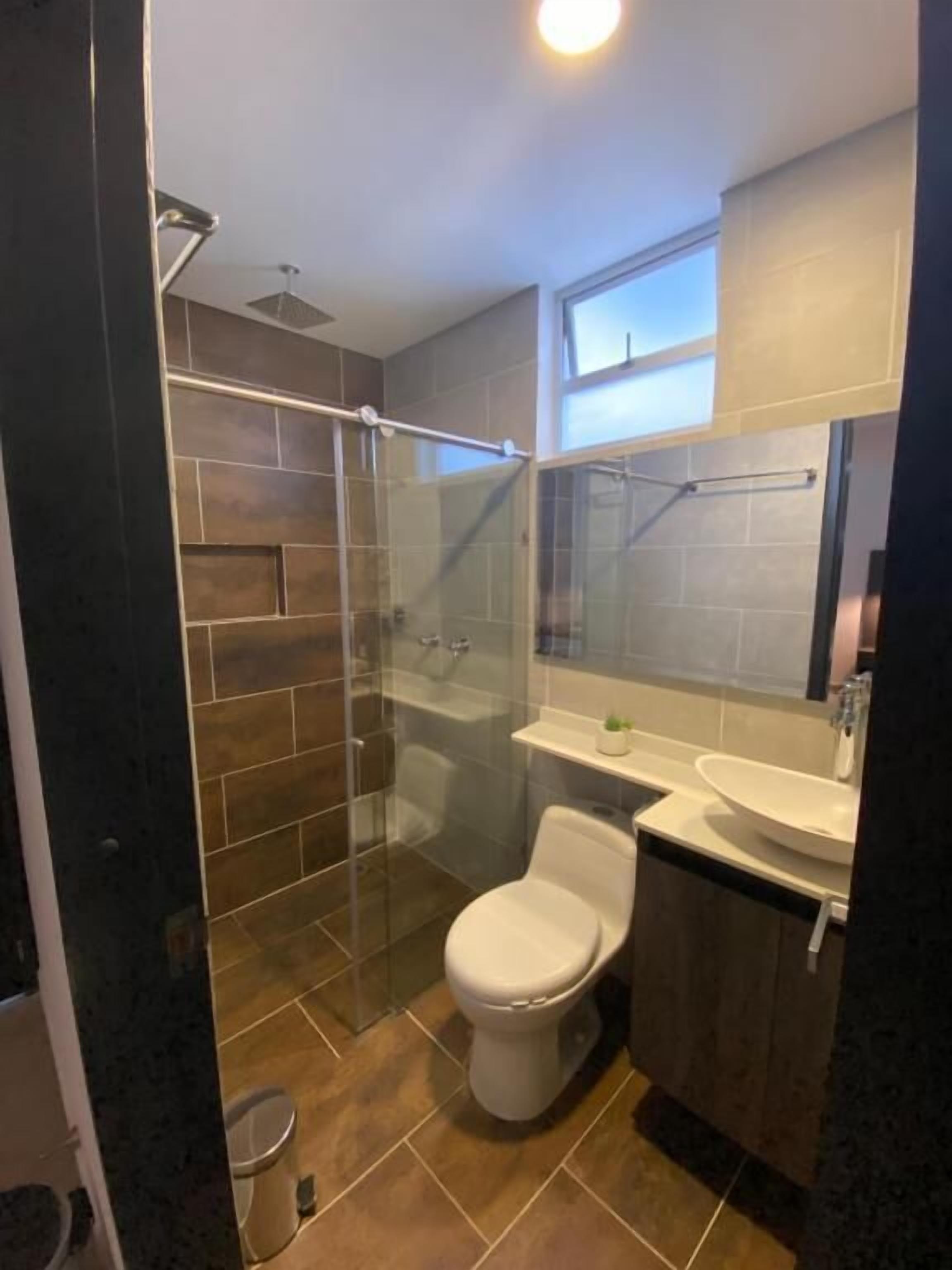 A modern bathroom with a glass shower enclosure, a toilet, and a sink.