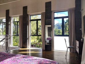 Un'ampia camera da letto con grandi finestre, un letto, una sedia e una scrivania.