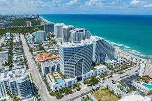 A high-rise hotel with a curved facade, located near a beach with a view of the ocean. - W Resort | Largest Corner | 1,737 SF | 270° Views (Fort Lauderdale)