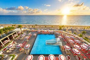 A resort pool area with a large pool, sun loungers, and umbrellas, overlooking a beach and ocean. - W Resort | Largest Corner | 1,737 SF | 270° Views (Fort Lauderdale)