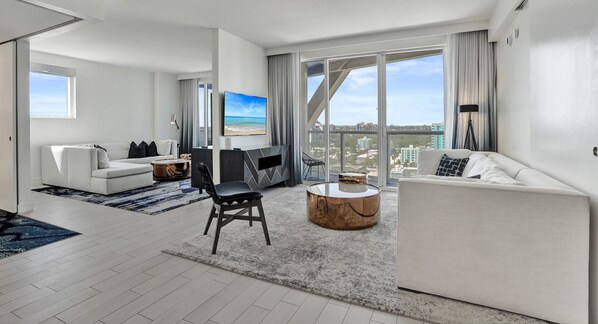 A modern living room with a large window, a flat-screen TV, a sofa, a coffee table, and a chair. - W Resort | Largest Corner | 1,737 SF | 270° Views (Fort Lauderdale)