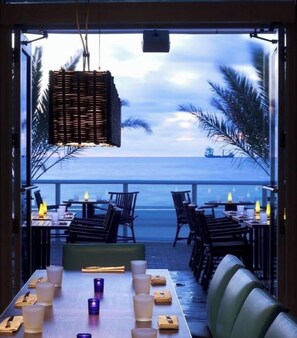 An outdoor dining area with tables and chairs, overlooking a body of water. - W Resort | Largest Corner | 1,737 SF | 270° Views (Fort Lauderdale)