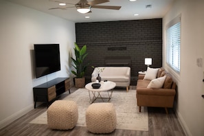A modern living room with a flat-screen TV, two sofas, a coffee table, and a potted plant. - Spacious 3-bedroom house in peaceful Clovis with AC (Clovis)
