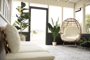 A room with a white sofa, a wicker chair, and potted plants. - Sunnyside A - Spacious 3-bedroom house in peaceful Clovis with AC (Clovis)