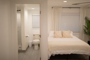 A bedroom with a bed, a bedside plant, a window with curtains, and a view of the bathroom. - Spacious 3-bedroom house in peaceful Clovis with AC (Clovis)