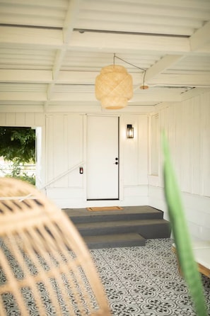 Una escalera conduce a una puerta con un muro texturizado y una lámpara colgante.