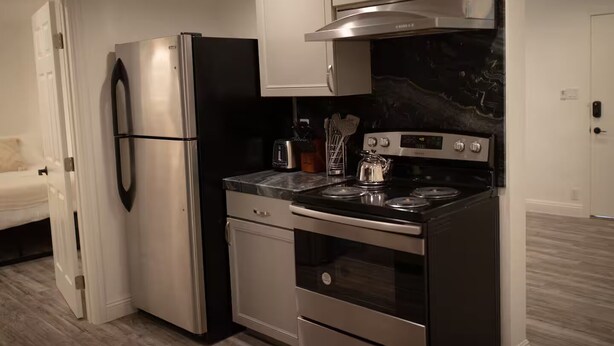 Une cuisine de taille réduite équipée d’un réfrigérateur, d’un four et d’une plaque de cuisson.