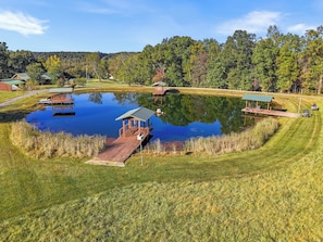 A pond with a wooden dock and a gazebo, surrounded by a well-maintained lawn and trees.