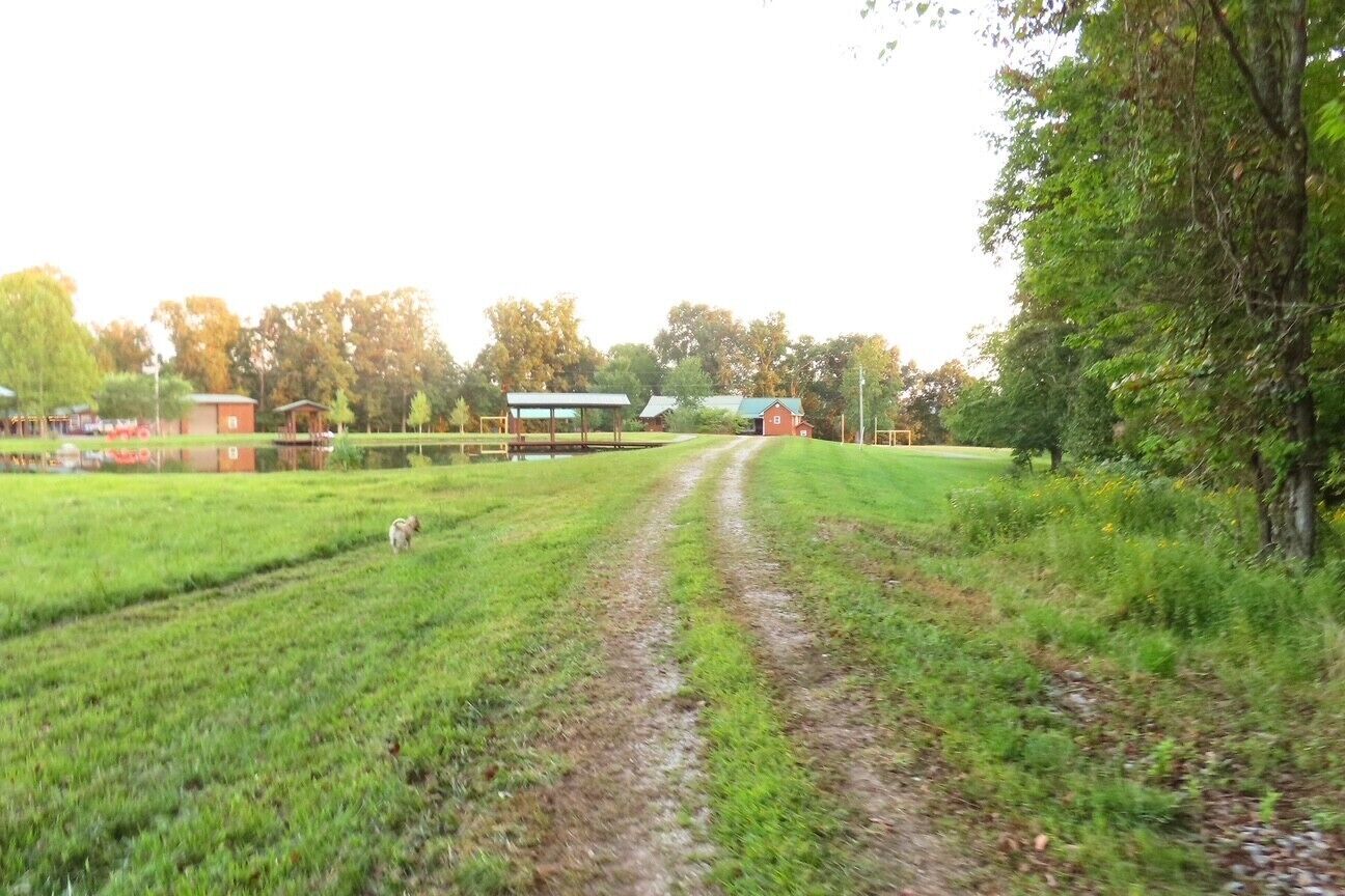 Un paysage rural avec un chemin de terre menant à une grange rouge.