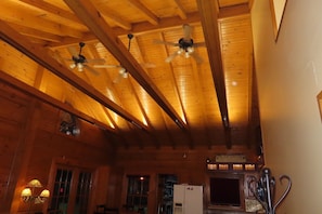 A wooden interior with exposed beams, a ceiling fan, and a refrigerator.