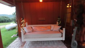 Una zona salotto esterna accogliente con una panca imbottita, un tappeto decorativo e luci a tendina.