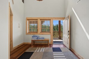 Un couloir au plancher de bois, un banc avec des serviettes pliées, et une porte donnant sur un balcon.
