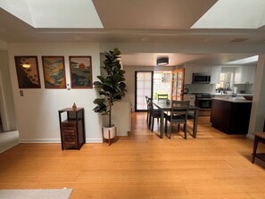 Un amplio espacio habitable con una mesa de comedor, sillas, una planta en maceta y una obra de arte en la pared.