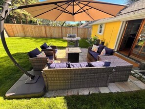 An outdoor patio with wicker furniture, a grill, and a large umbrella. - Peaceful Retreat near Airport & Downtown Seattle (Seattle)