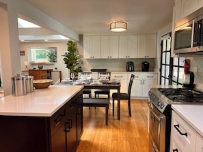 A modern kitchen with white cabinets, a central island, and a gas stove. - Peaceful Retreat near Airport & Downtown Seattle (Seattle)