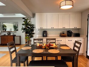 A modern kitchen with white cabinets, a dining table set with placemats, and a coffee maker. - Peaceful Retreat near Airport & Downtown Seattle (Seattle)