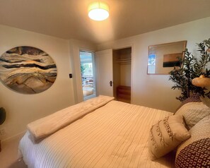 A bedroom with a bed, a painting, a door leading to another room, and a plant. - Peaceful Retreat near Airport & Downtown Seattle (Seattle)