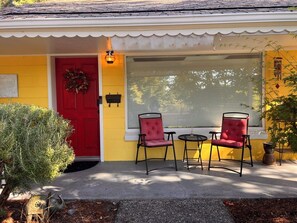 A yellow house with a red door, two red chairs, a small table, and a potted plant. - Peaceful Retreat near Airport & Downtown Seattle (Seattle)