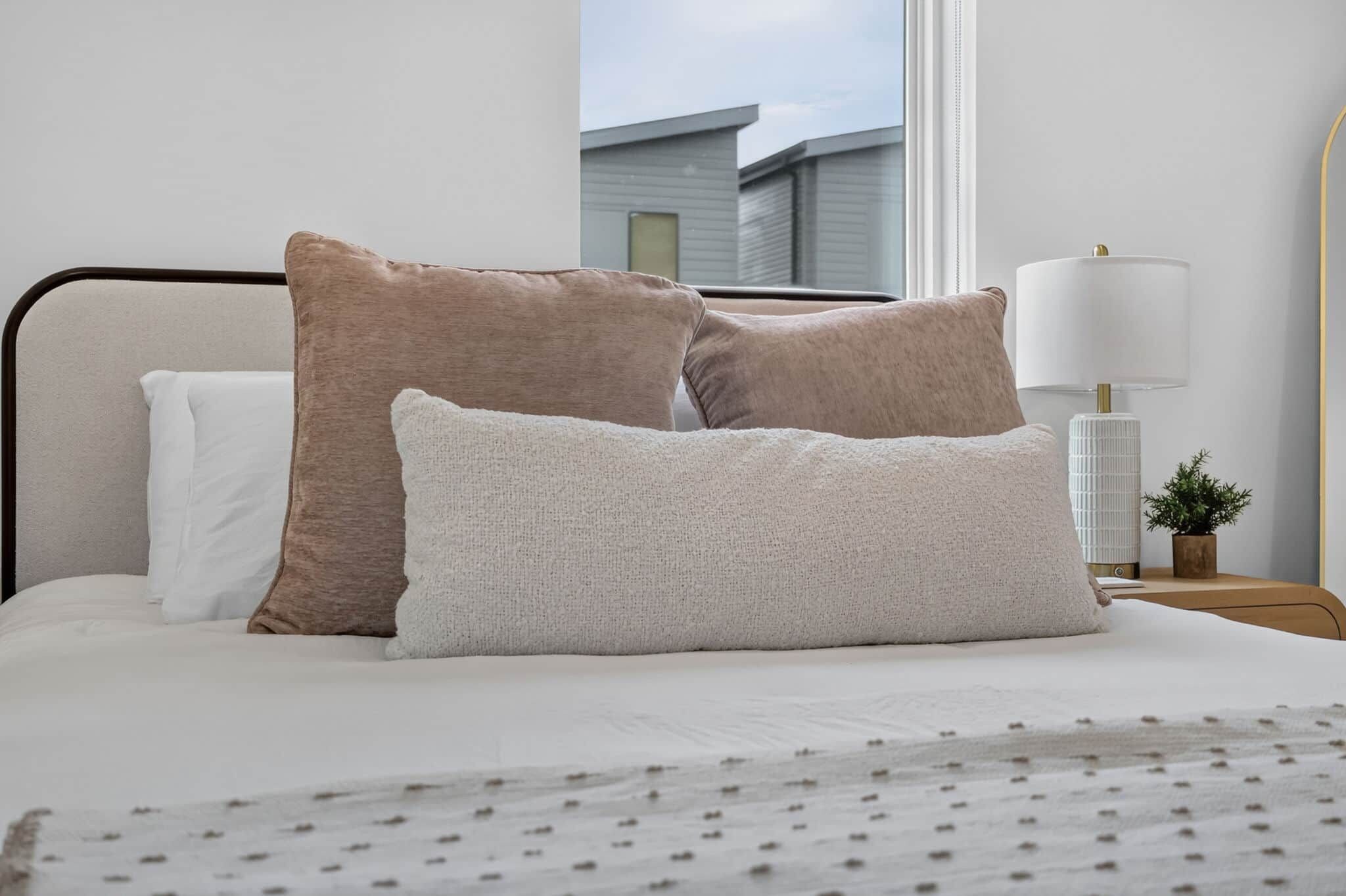 Un lit bien fait, avec trois oreillers et un couvre-lit blanc.