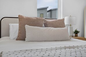 A neatly made bed with three pillows and a white bedspread.