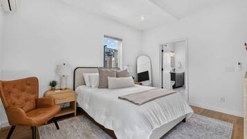 A bedroom with a bed, a chair, a nightstand, a mirror, and a window.