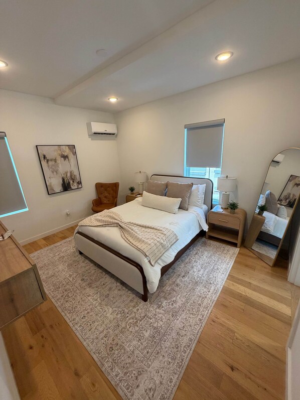 A bedroom with a bed, bedside tables, a mirror, and a window.