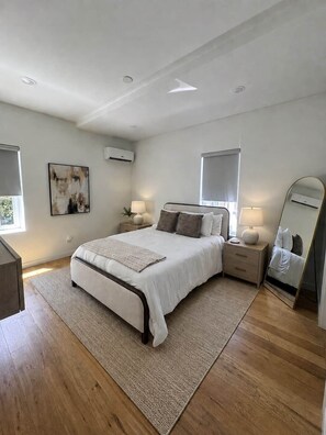 A modern bedroom with a large bed, bedside tables, a mirror, and artwork on the wall. - The Saint Luxury Townhome: steps to UTK/Downtown (Knoxville)