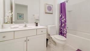 Une salle de bain moderne avec un lavabo, des toilettes et une zone de douche, le tout de couleur blanche.