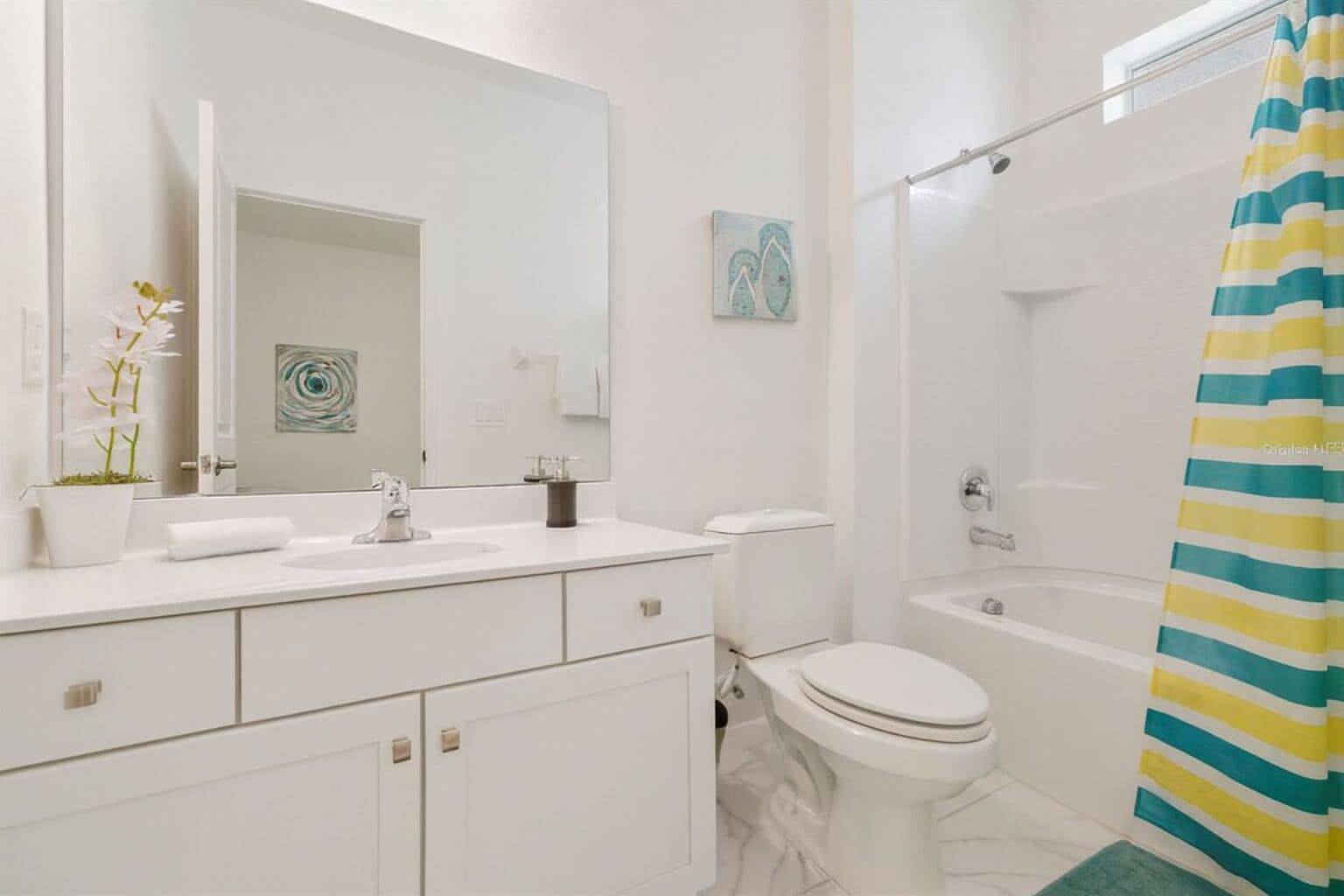 Un baño moderno con lavamanos, espejo, inodoro y ducha blancos.