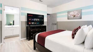 Une chambre d’hôtel avec un lit, un téléviseur diffusant Netflix, une commode et une porte donnant sur une autre pièce.