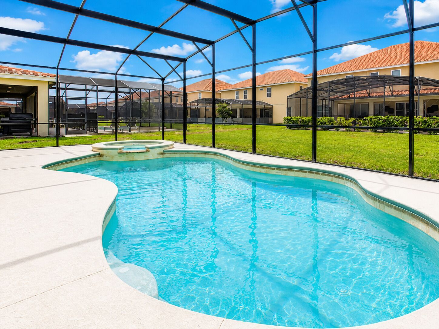 Una piscina de borde curvo, rodeada por un recinto de cristal, con vista a edificios residenciales al fondo.