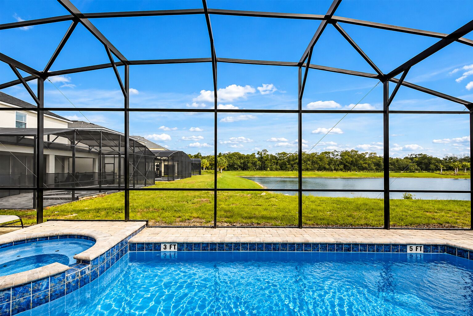 A swimming pool with a clear view of a lake and a grassy area beyond.