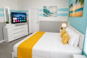 Una habitación de hotel con una cama, un televisor en una cómoda, una puerta y una pared con un cuadro.