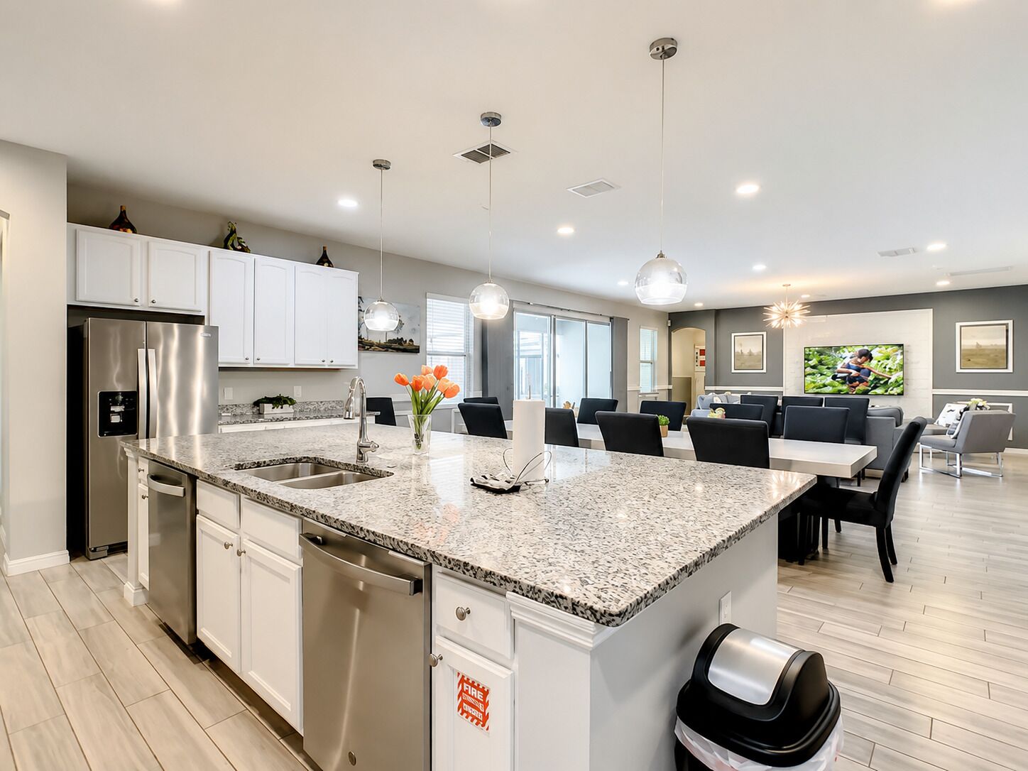 A modern kitchen with stainless steel appliances, a granite countertop, and a dining area with a large table and chairs.