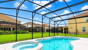 Une piscine avec un jacuzzi, entourée d’un patio couvert d’où l’on peut admirer la vue sur les maisons.