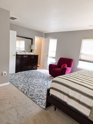Un dormitorio con cama, cómoda, silla y ventana.