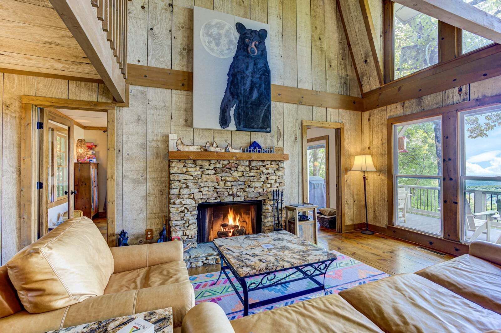 Una habitación acogedora con chimenea de piedra, un sofá y un cuadro de un oso.